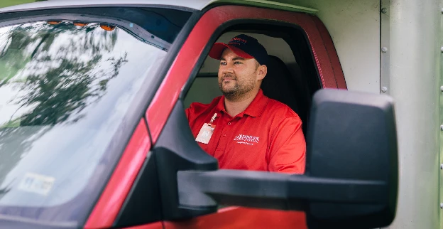 Rainbow Restoration service professional driving a red, branded vehicle.