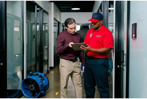 Rainbow Restoration service professional discusses commercial storm damage restoration services with a client.